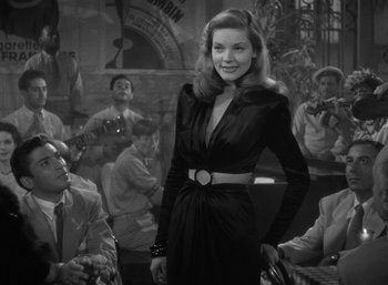 Movie still from “To Have and Have Not” (1944), directed by Howard Hawks – A black and white photo of a woman in a black dress; Medium shot, Over the shoulder angle