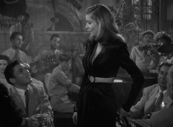 Movie still from “To Have and Have Not” (1944), directed by Howard Hawks – A black and white photo of a woman in a black dress; Medium shot, Over the shoulder angle