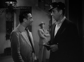 Movie still from “To Have and Have Not” (1944), directed by Howard Hawks – Two men are talking to each other in a black and white photo; Medium shot, Low angle