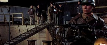 Movie still from “Tobruk” (1967), directed by Arthur Hiller – A group of men standing on top of a dock; Medium shot, Low angle