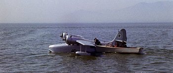 Movie still from “Tobruk” (1967), directed by Arthur Hiller – An airplane is floating in the water near a small boat; Extreme Wide shot, High angle