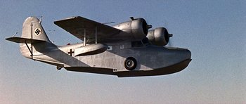 Movie still from “Tobruk” (1967), directed by Arthur Hiller – An airplane flying through the air on a sunny day; Wide shot, Low angle