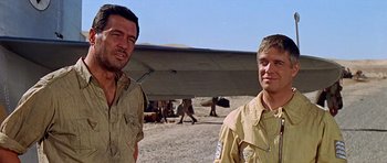 Movie still from “Tobruk” (1967), directed by Arthur Hiller – Two men standing next to each other on a dirt field; Medium shot, Low angle