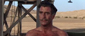 Movie still from “Tobruk” (1967), directed by Arthur Hiller – A man with a mustache is standing in the desert; Close Up shot, Over the shoulder angle