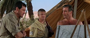 Movie still from “Tobruk” (1967), directed by Arthur Hiller – A man standing in front of a tent with another man standing next to him; Medium shot, Over the shoulder angle