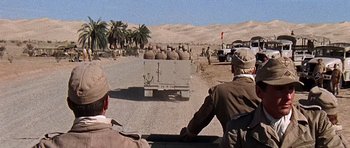 Movie still from “Tobruk” (1967), directed by Arthur Hiller – A group of men riding on the back of an army vehicle; Wide shot, High angle