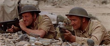 Movie still from “Tobruk” (1967), directed by Arthur Hiller – Two men in military uniforms are sitting on the ground; Medium shot, Low angle