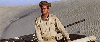 Movie still from “Tobruk” (1967), directed by Arthur Hiller – A man in a military uniform standing in front of an airplane; Medium shot, Low angle