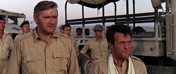 Movie still from “Tobruk” (1967), directed by Arthur Hiller – A group of men standing next to each other in a field; Close Up shot, Low angle