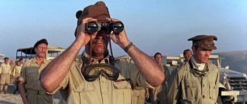 Movie still from “Tobruk” (1967), directed by Arthur Hiller – A man looking through a pair of binoculars; Close Up shot, Low angle