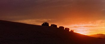 Movie still from “Tobruk” (1967), directed by Arthur Hiller – A group of vehicles driving on top of a hill at sunset; Extreme Wide shot, Low angle