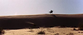 Movie still from “Tobruk” (1967), directed by Arthur Hiller – A person riding a horse in the middle of the desert; Extreme Wide shot, Low angle