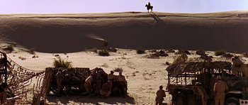 Movie still from “Tobruk” (1967), directed by Arthur Hiller – A group of men sitting on top of a dirt hill; Extreme Wide shot, Low angle