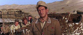 Movie still from “Tobruk” (1967), directed by Arthur Hiller – A group of men standing next to each other in a field; Close Up shot, Low angle