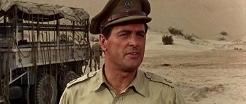 Movie still from “Tobruk” (1967), directed by Arthur Hiller – A man in a military uniform is standing in the desert; Close Up shot, Low angle