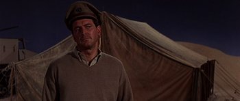 Movie still from “Tobruk” (1967), directed by Arthur Hiller – A man wearing a hat standing in front of a tent; Close Up shot, Low angle