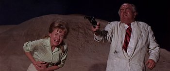Movie still from “Tobruk” (1967), directed by Arthur Hiller – A man and a woman in the sand with a gun pointed at them; Medium shot, Low angle