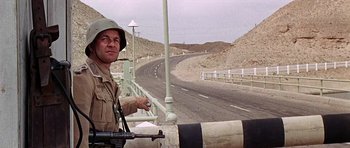 Movie still from “Tobruk” (1967), directed by Arthur Hiller – A man in a military uniform standing next to a road; Medium shot, Low angle