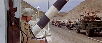 Movie still from “Tobruk” (1967), directed by Arthur Hiller – A group of men riding motorcycles down a street; Medium shot, Low angle