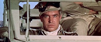 Movie still from “Tobruk” (1967), directed by Arthur Hiller – A man wearing a hat and glasses; Close Up shot, Low angle