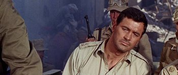 Movie still from “Tobruk” (1967), directed by Arthur Hiller – A man with a gun in his hand and a man with a gun in his other hand; Close Up shot, Over the shoulder angle