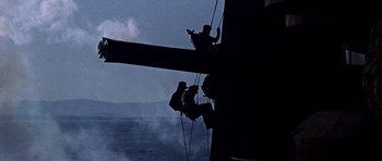 Movie still from “Tobruk” (1967), directed by Arthur Hiller – Two men on a rope are hanging from the side of a tall building; Wide shot, Low angle