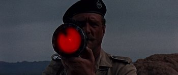 Movie still from “Tobruk” (1967), directed by Arthur Hiller – A man in a military uniform holding an object in front of his face; Close Up shot, Low angle