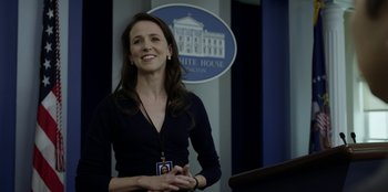 Movie still from “House of Cards” (2013), created by Beau Willimon – A woman standing in front of a podium in front of the white house; Close Up shot, Over the shoulder angle