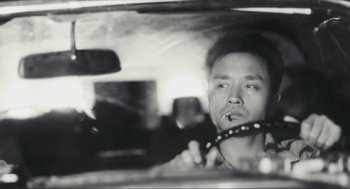 Movie still from “Happy Together” (1997), directed by Kar-Wai Wong – A black and white photo of a man in a car; Close Up shot, Low angle
