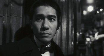 Movie still from “Happy Together” (1997), directed by Kar-Wai Wong – A black and white photo of a man wearing a suit and bow tie; Close Up shot, Low angle