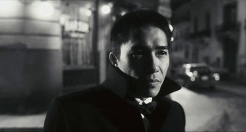Movie still from “Happy Together” (1997), directed by Kar-Wai Wong – A black and white photo of a man wearing a suit and bow tie; Close Up shot, Low angle