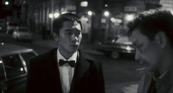 Movie still from “Happy Together” (1997), directed by Kar-Wai Wong – A man wearing a suit and a bow tie standing on the street; Close Up shot, Over the shoulder angle