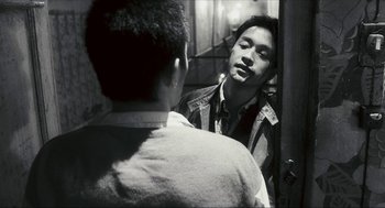 Movie still from “Happy Together” (1997), directed by Kar-Wai Wong – A black and white photo of a man looking at himself in the mirror; Close Up shot, Over the shoulder angle