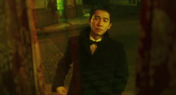 Movie still from “Happy Together” (1997), directed by Kar-Wai Wong – A man wearing a suit and tie standing on the sidewalk; Medium shot, Low angle