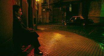 Movie still from “Happy Together” (1997), directed by Kar-Wai Wong – A person sitting on a chair on a sidewalk at night; Wide shot, High angle
