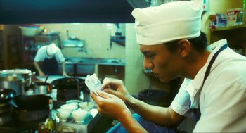 Movie still from “Happy Together” (1997), directed by Kar-Wai Wong – A man wearing a white hat is looking at a piece of paper; Close Up shot, Low angle