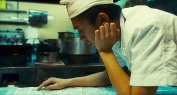Movie still from “Happy Together” (1997), directed by Kar-Wai Wong – A man wearing a chef's hat looking at a map; Close Up shot, High angle