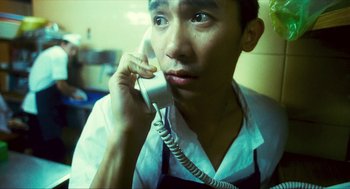 Movie still from “Happy Together” (1997), directed by Kar-Wai Wong – A man holding a phone up to his ear; Close Up shot, High angle