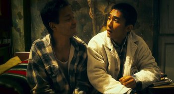 Movie still from “Happy Together” (1997), directed by Kar-Wai Wong – Two young men sitting next to each other in a room; Medium shot, Low angle