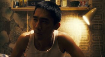 Movie still from “Happy Together” (1997), directed by Kar-Wai Wong – A young man in a white tank top is looking at the camera; Close Up shot, Low angle