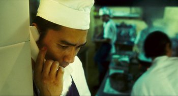 Movie still from “Happy Together” (1997), directed by Kar-Wai Wong – A man wearing a chef's hat in a kitchen; Close Up shot, High angle