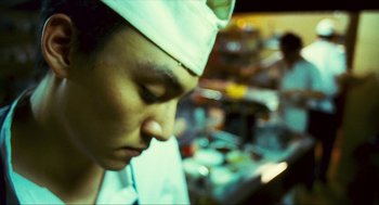 Movie still from “Happy Together” (1997), directed by Kar-Wai Wong – A man wearing a white hat in a kitchen; Close Up shot, Low angle