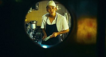 Movie still from “Happy Together” (1997), directed by Kar-Wai Wong – A man in an apron is holding a spatula in a kitchen; Close Up shot, Low angle