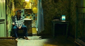 Movie still from “Happy Together” (1997), directed by Kar-Wai Wong – A person sitting on a bench in a room; Wide shot, High angle
