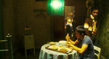 Movie still from “Happy Together” (1997), directed by Kar-Wai Wong – A young boy sitting at a table eating pizza; Wide shot, Over the shoulder angle