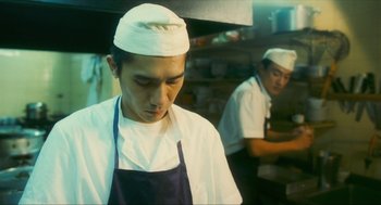 Movie still from “Happy Together” (1997), directed by Kar-Wai Wong – A man in a chef's hat in a restaurant kitchen; Medium shot, Low angle