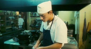 Movie still from “Happy Together” (1997), directed by Kar-Wai Wong – A man in a chef's hat and apron in a kitchen; Medium shot, Low angle