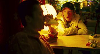 Movie still from “Happy Together” (1997), directed by Kar-Wai Wong – Two men are sitting at a table and one of them is drinking a beverage; Close Up shot, Over the shoulder angle