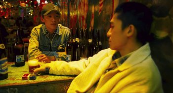 Movie still from “Happy Together” (1997), directed by Kar-Wai Wong – Two men sitting at a bar with beer bottles in front of them; Medium shot, High angle