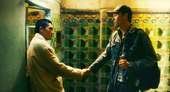 Movie still from “Happy Together” (1997), directed by Kar-Wai Wong – Two young men shaking hands in front of a wall; Medium shot, Low angle
